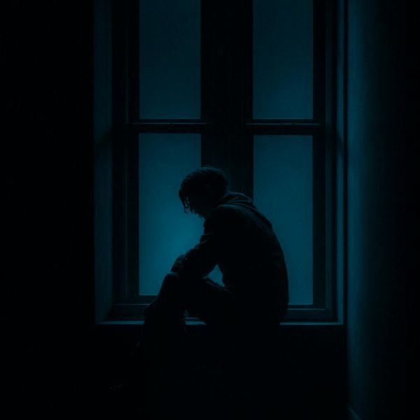 Person meditating peacefully by a window with soft light coming in.
